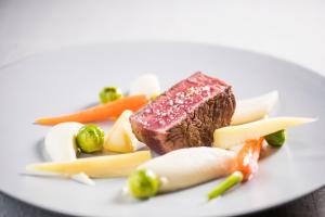 a white plate topped with meat and vegetables at Hostellerie Des Châteaux & Spa in Ottrott