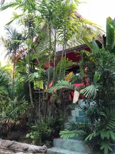a garden in front of a building with palm trees at Ruan Mai San Ngam Resort - SHA Plus in Nai Yang Beach
