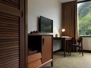 a hotel room with a desk with a television and a window at Yusense Hotel in Taipei