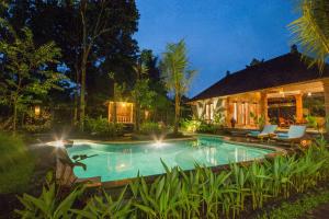 a swimming pool in front of a house at night at Jero Sebali Villa in Ubud