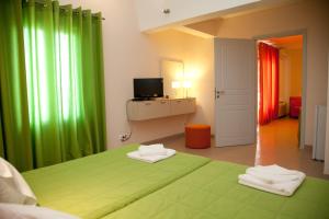 a bedroom with a green bed and a television at Atrium Villa in Fira