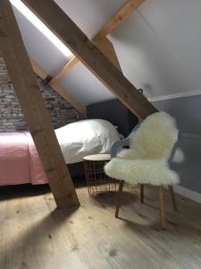 a bedroom with a bed and a white chair at B&B Erve ten Dam in Ambt Delden