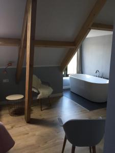 La salle de bains est pourvue d'une baignoire blanche et d'une table. dans l'établissement B&B Erve ten Dam, à Ambt Delden