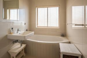 a bathroom with a white tub and a sink at Luxurious Beach Front in Strand +14 photos