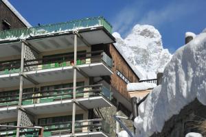 un bâtiment recouvert de neige avec une montagne en arrière-plan dans l'établissement Mollino Rooms, à Breuil-Cervinia