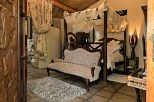a bedroom with a canopy bed and a chair at De Loft Guesthouse in Piet Retief