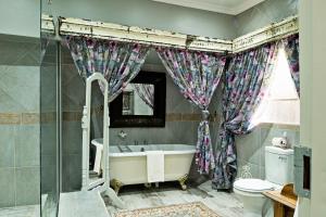 a bathroom with a tub and a toilet and a window at De Loft Guesthouse in Piet Retief +33 photos