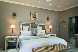 a bedroom with a large bed with two tables and two lamps at De Loft Guesthouse in Piet Retief