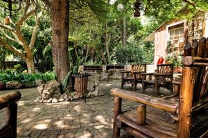 a patio with benches and a table and trees at De Loft Guesthouse in Piet Retief