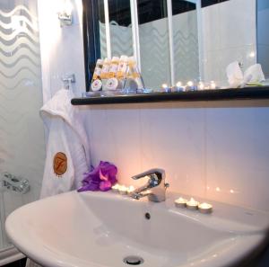lavabo blanco en el baño con espejo en Flisvos Hotel Nafpaktos, en Nafpaktos