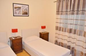 two twin beds in a room with a window at BJB Apartamento in Olhão
