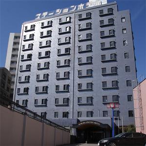 a large white building with a sign on it at Kurume Station Hotel in Kurume