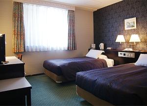 a hotel room with two beds and a window at Kurume Station Hotel in Kurume