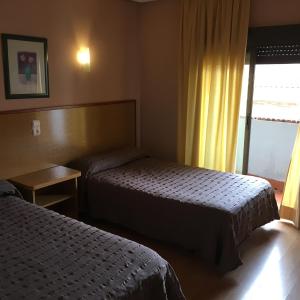 a hotel room with two beds and a window at Hotel Avenida Leganés in Leganés