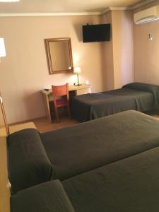 a hotel room with two beds and a table and a chair at Hotel Avenida Leganés in Leganés
