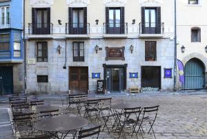 un grupo de mesas y sillas frente a un edificio en Albergue Plaza Catedral, en Pamplona