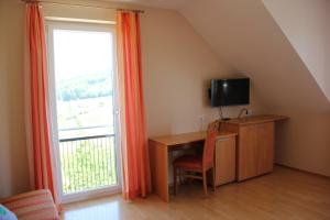 a room with a desk with a television and a window at Zweytick Gästezimmer Weingut in Ratsch an der Weinstraße