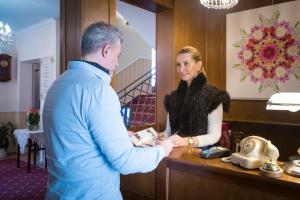 a man and a woman shaking hands at a counter at Hotel Bojnický Vínny Dom in Bojnice