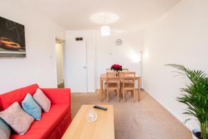 a living room with a red couch and a table at Comfy 2BR Flat with Wi-Fi in Bishop's Stortford in Bishops Stortford