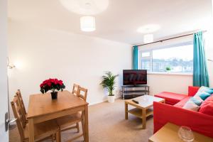 a living room with a red couch and a table at Comfy 2BR Flat with Wi-Fi in Bishop's Stortford in Bishops Stortford