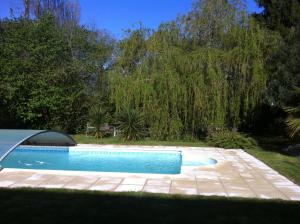 a swimming pool in a yard with a tree at Le Jardin Fleuri in Ploemel