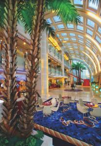 a lobby with a palm tree and tables and chairs at Bayshore Hotel Dalian in Dalian
