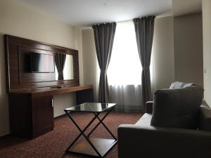 sala de estar con TV, sofá y mesa en Hotel Best en Ploieşti