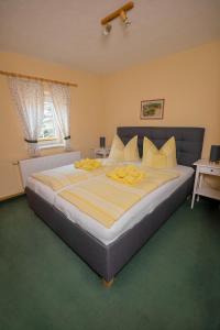 a bedroom with a large bed with yellow pillows at Pension Immergrün in Kurort Jonsdorf