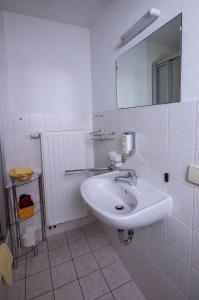 W białej łazience znajduje się umywalka i lustro. w obiekcie Pension Immergrün w mieście Kurort Jonsdorf