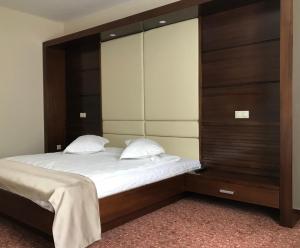 a bedroom with a large bed with a wooden headboard at Hotel Best in Ploieşti