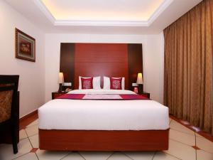 a bedroom with a large bed with a wooden headboard at Emarald Suites, Cochin in Cochin
