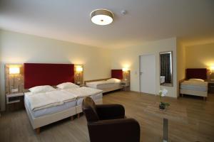 una camera d'albergo con due letti e una sedia di Hotel am Pferdemarkt a Rotenburg an der Wümme