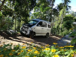 a white van parked on a dirt road with flowers at Ella Sunrise in Ella