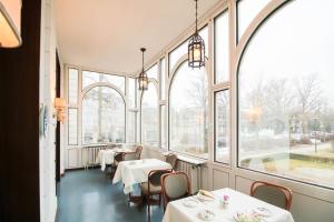 un restaurant avec des tables blanches, des chaises et des fenêtres dans l'établissement Hotel Axel Springer, à Berlin