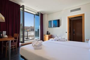 Habitación de hotel con 2 camas, escritorio y ventana en Abba Sants en Barcelona