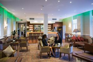 two women sitting at tables in a hotel lobby at Oakley Hall Hotel in Basingstoke