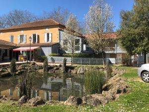 a house with a pond in front of it at Le bistrot d eugenie in Eugénie-les-Bains