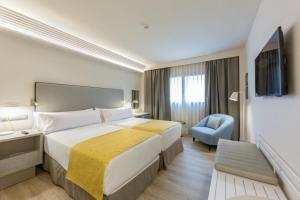 um quarto de hotel com uma cama grande e uma cadeira em Catalonia Granada em Granada