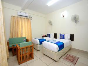 a bedroom with two beds and a chair in it at Sophiya Suites in Cochin