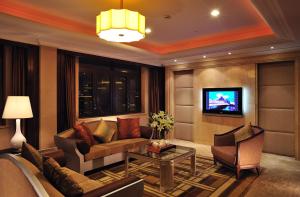 a living room with a couch and a tv at Broadway Mansions Hotel - Bund in Shanghai