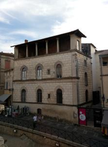 an old brick building with a woman standing in front of it at Palais de Luppé, Chambre d'hôtes in Arles