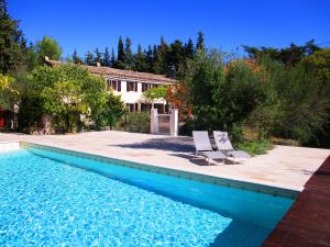 a swimming pool with two chairs and a house at Le mas des Lilas in Uzès