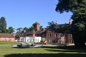 a large red brick building with a clock tower at Oakley Hall Hotel in Basingstoke