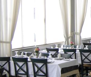 a dining room with tables and chairs and large windows at Ilis Hotel in Olympia