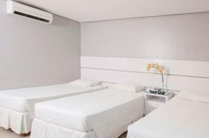 a white room with two beds and a table at Brisa Tower Hotel in Ceilândia