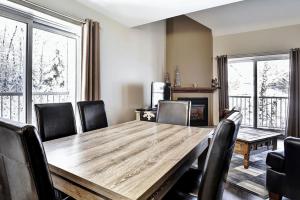 a dining room with a wooden table and chairs at Condo 306 33 Chemin du Hameau by Les Chalets Alpins in Stoneham
