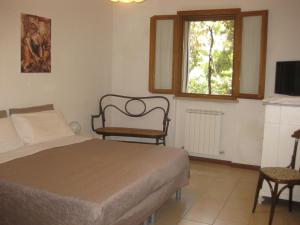 a bedroom with a bed and a chair and a window at Country House-B&B-Appartamenti Ai Cipressi in Urbino