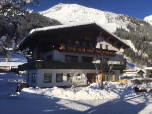 a large building in the snow with a snow covered mountain at Appartements Schwarzer Adler in Elbigenalp