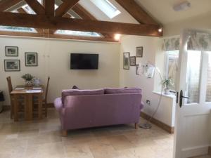 a living room with a purple couch and a tv at The Potting Shed in Warwick