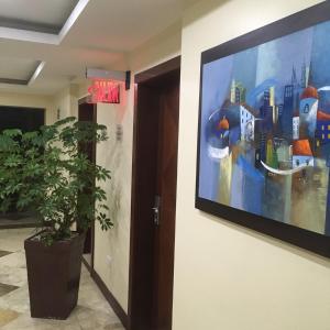 a large painting on a wall next to a plant at Suites Parque Real in Quito